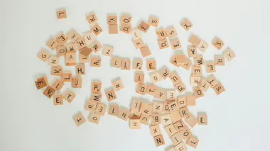 Lettres en bois de jeu de lettres éparpillées sur un fond blanc, vues du dessus
